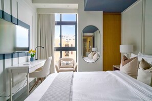 Ein Hotelzimmer mit einem großen Bett, einem Schreibtisch mit Stuhl, einem Spiegel und Blick nach draußen.