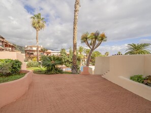 A paved courtyard with palm trees, a pool, and buildings with balconies. - La Mareta Cozy Apartment With Pool (Brena Baja)