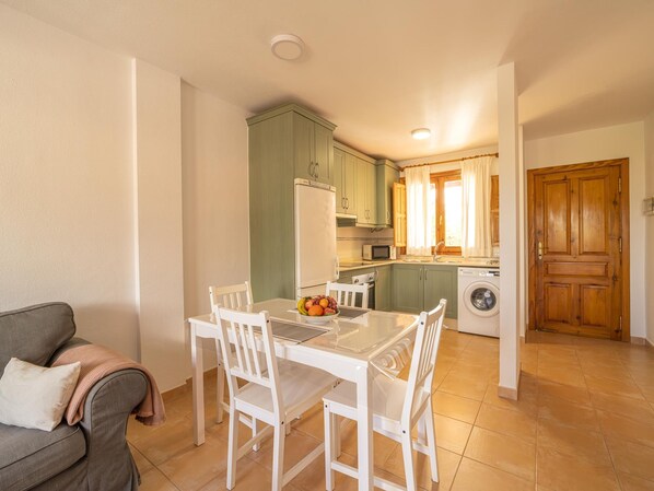 Un espace de vie compact comprenant un coin repas, une kitchenette et un lave-linge.