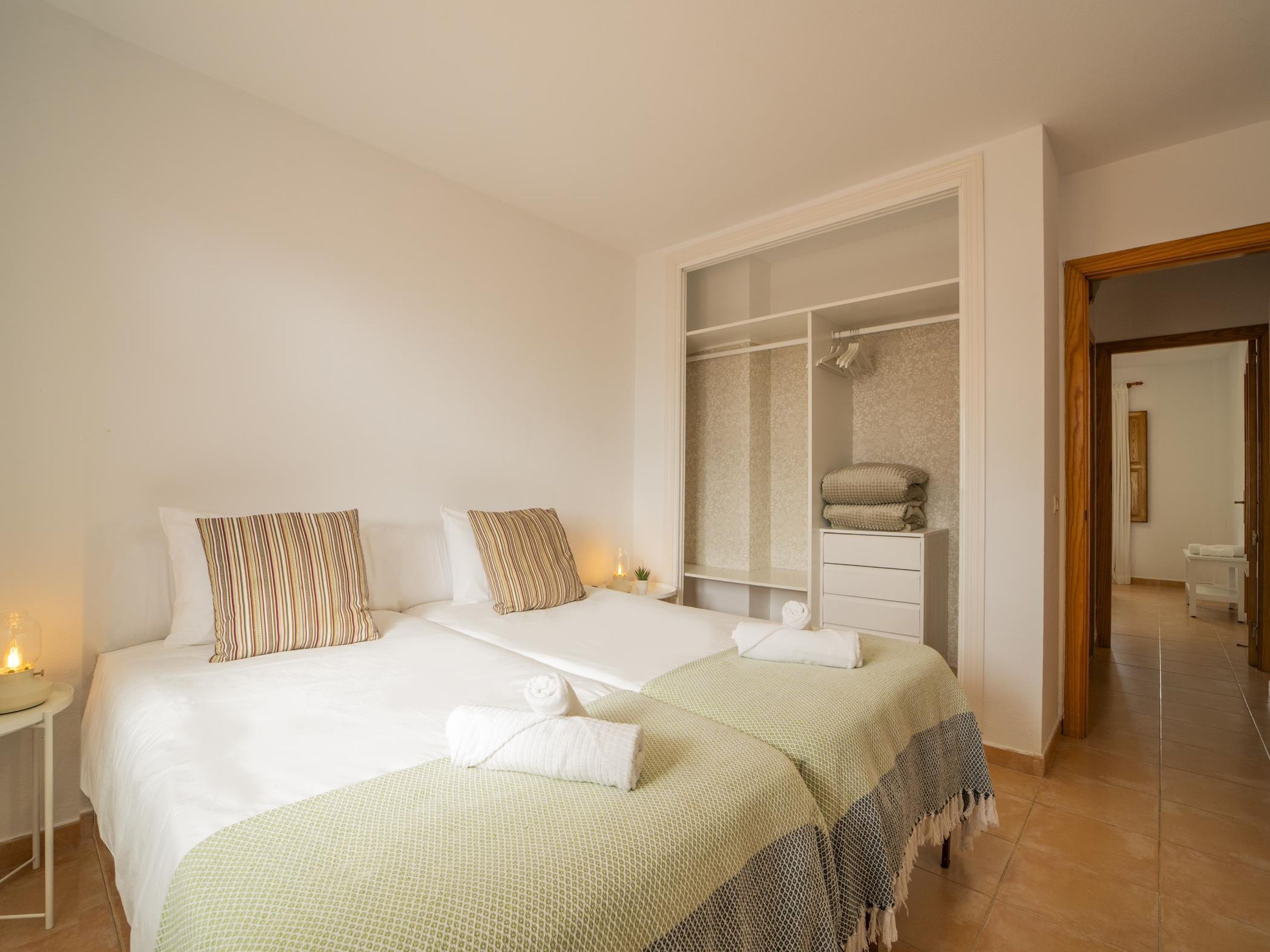 A bedroom with two beds, a walk-in closet, and a bathroom visible through an open door.