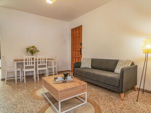 A living room with a grey sofa, a wooden coffee table, a dining table with white chairs, and a wooden door. - CHL Armon a Side see View in Puerto Naos (Los Llanos de Aridane)