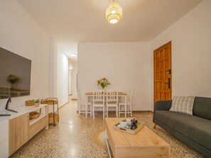 Uma sala de estar moderna com televisão, mesa de centro de madeira e um sofá.