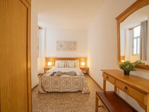 A bedroom with a bed, bedside tables, a mirror, and a small potted plant. - CHL Armon a Side see View in Puerto Naos (Los Llanos de Aridane)
