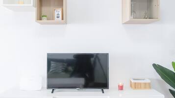 Una sala de estar moderna con un televisor de pantalla plana, estanterías de madera, una planta pequeña y una vela.