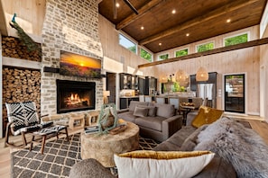 A spacious living room with a stone fireplace, wooden beams, and a large sofa. - New Listing Discount-Luxury-Modern-Mountain and Lake View w/ Jacuzzi & Fireplace (Blue Ridge)