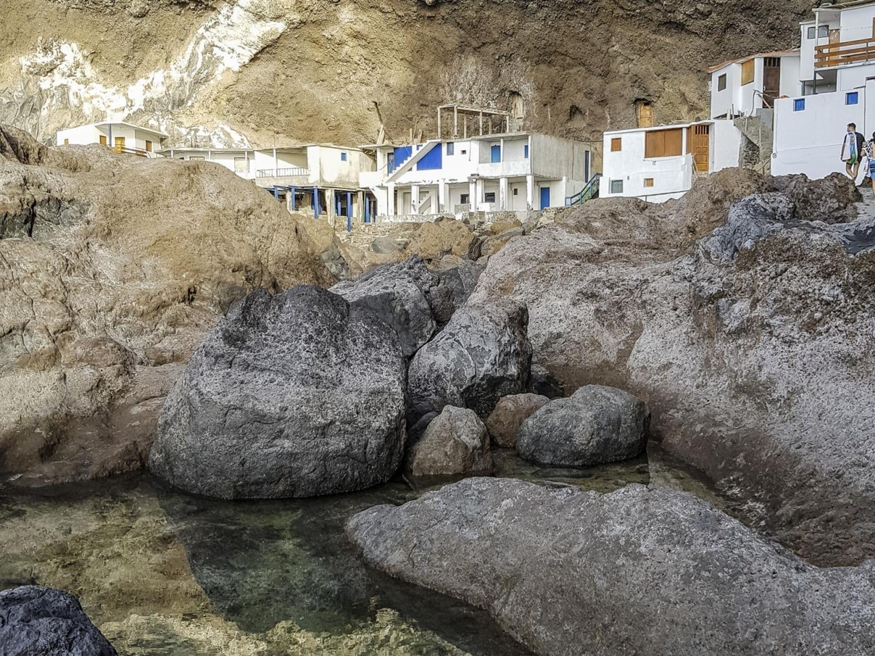 Un pueblo costero con edificios blancos, ubicado junto a un acantilado rocoso.