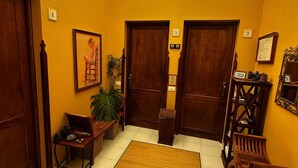 A hallway with three wooden doors, a bench, a potted plant, and a small table with a mirror and decorative items. - CHL Mayoysa La Palma Vista mar en Bre a Baja (Brena Baja)