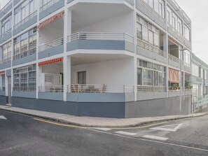 A modern multi-story building with balconies, large windows, and a flat roof.