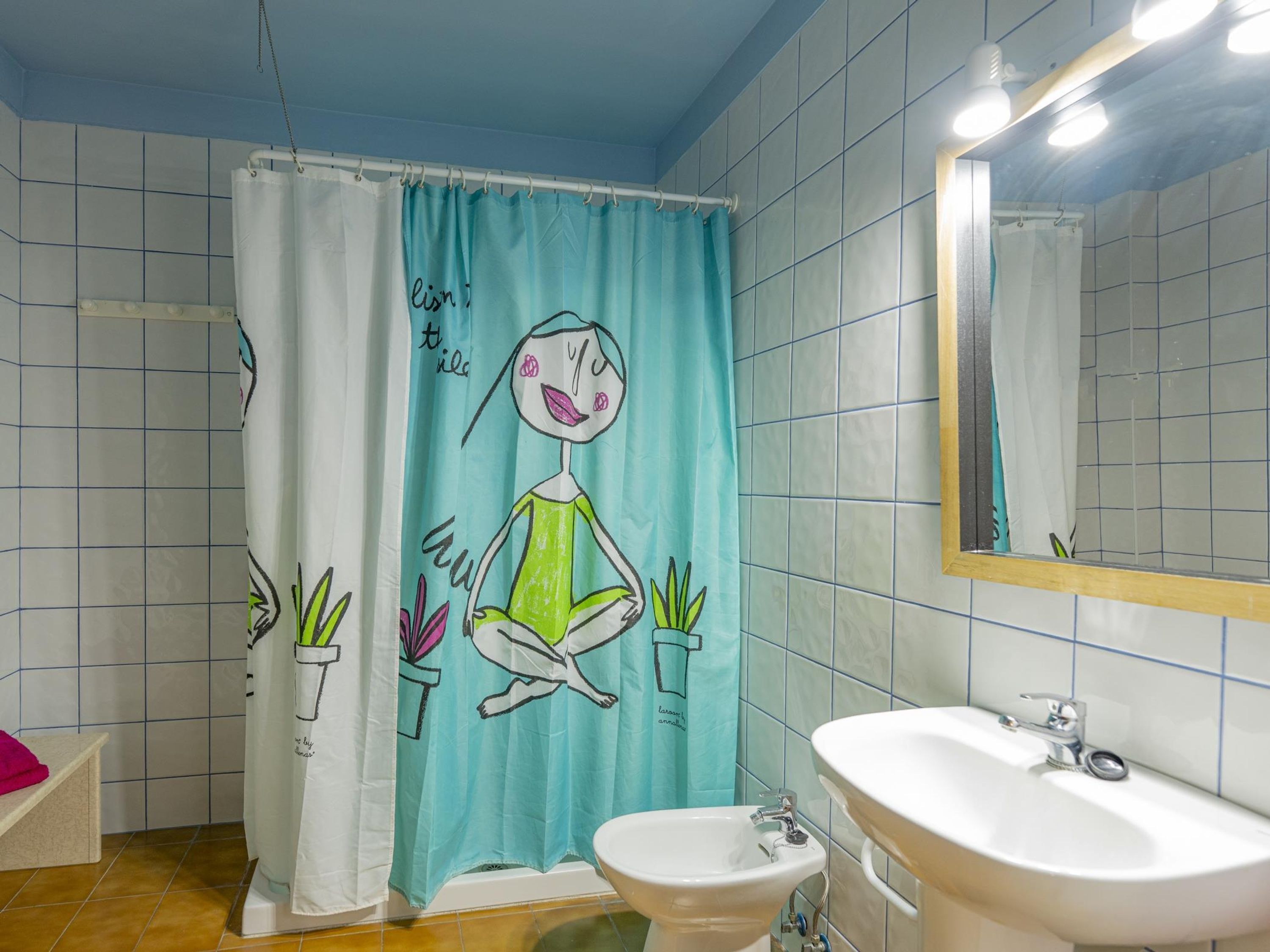 Une salle de bain avec un rideau de douche orné d’un personnage de dessin animé, un lavabo et un miroir.