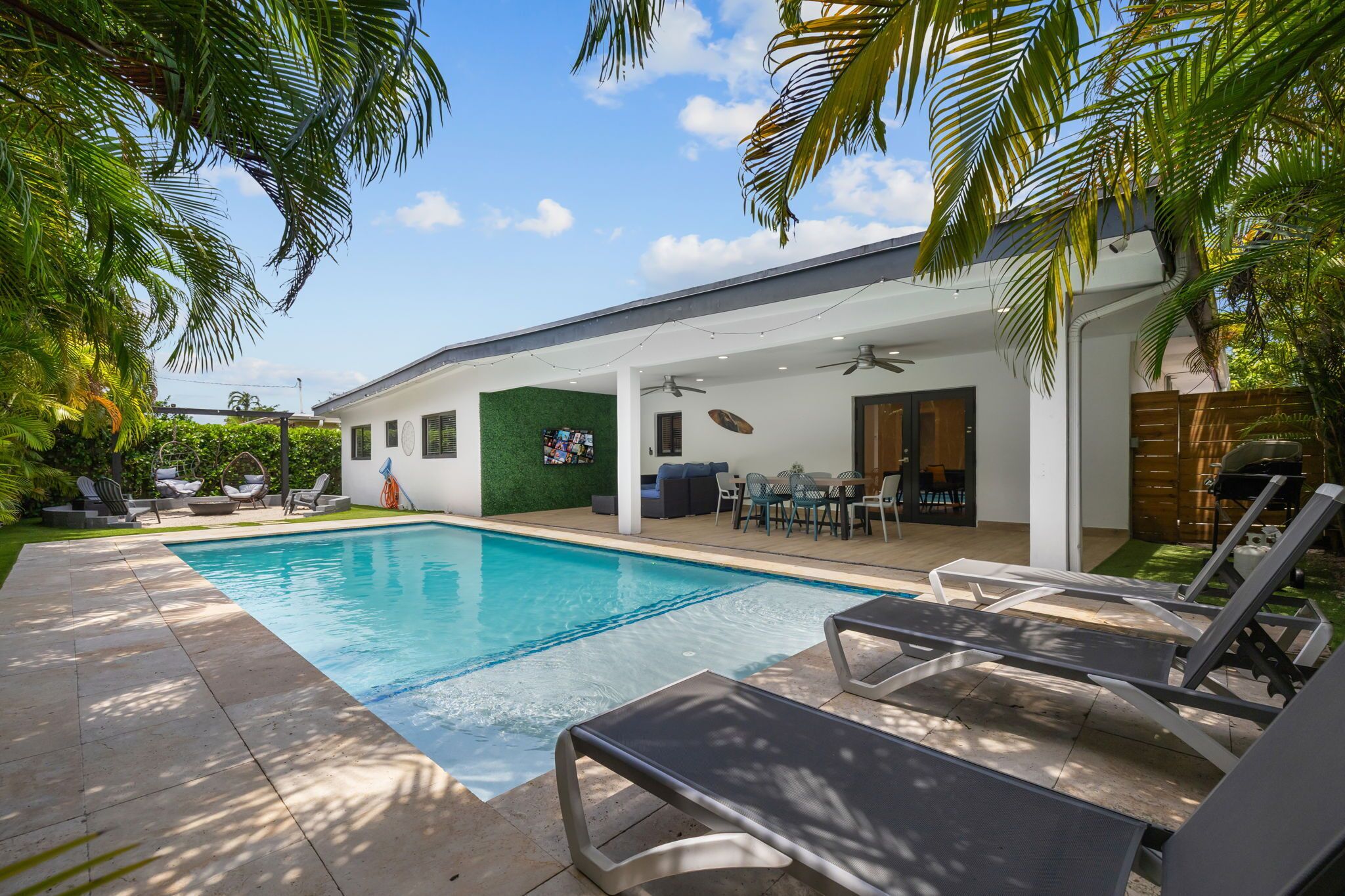 Ein modernes Haus mit Swimmingpool, Außenbereich mit Sitzgelegenheiten und einer überdachten Terrasse.