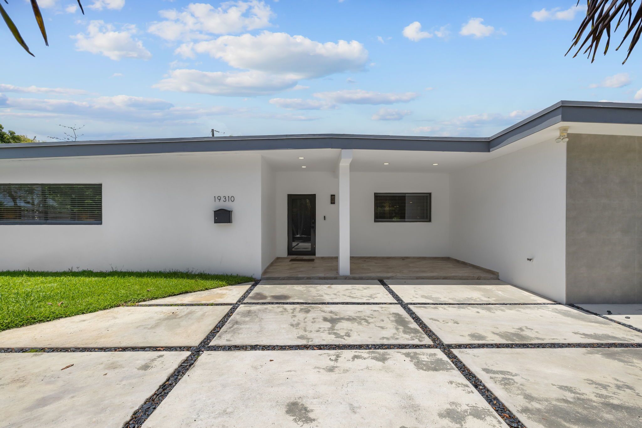 A modern building with a flat roof, a concrete entrance, and a number '19310' on the wall.