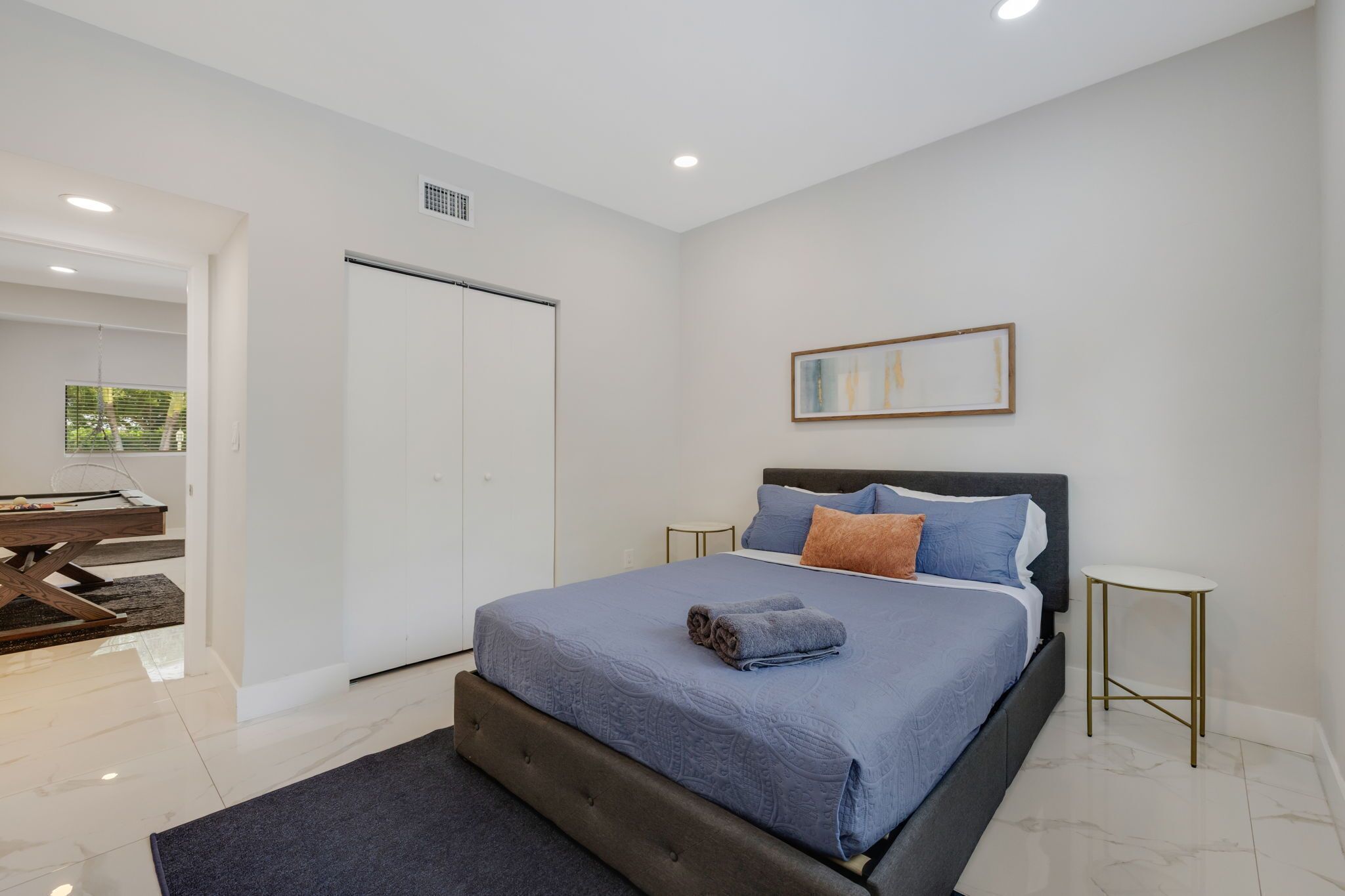 Quarto moderno com cama, mesas de cabeceira, guarda-roupa e vista para o exterior.