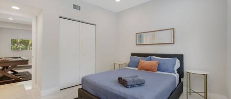 Quarto moderno com cama, mesas de cabeceira, guarda-roupa e vista para o exterior.
