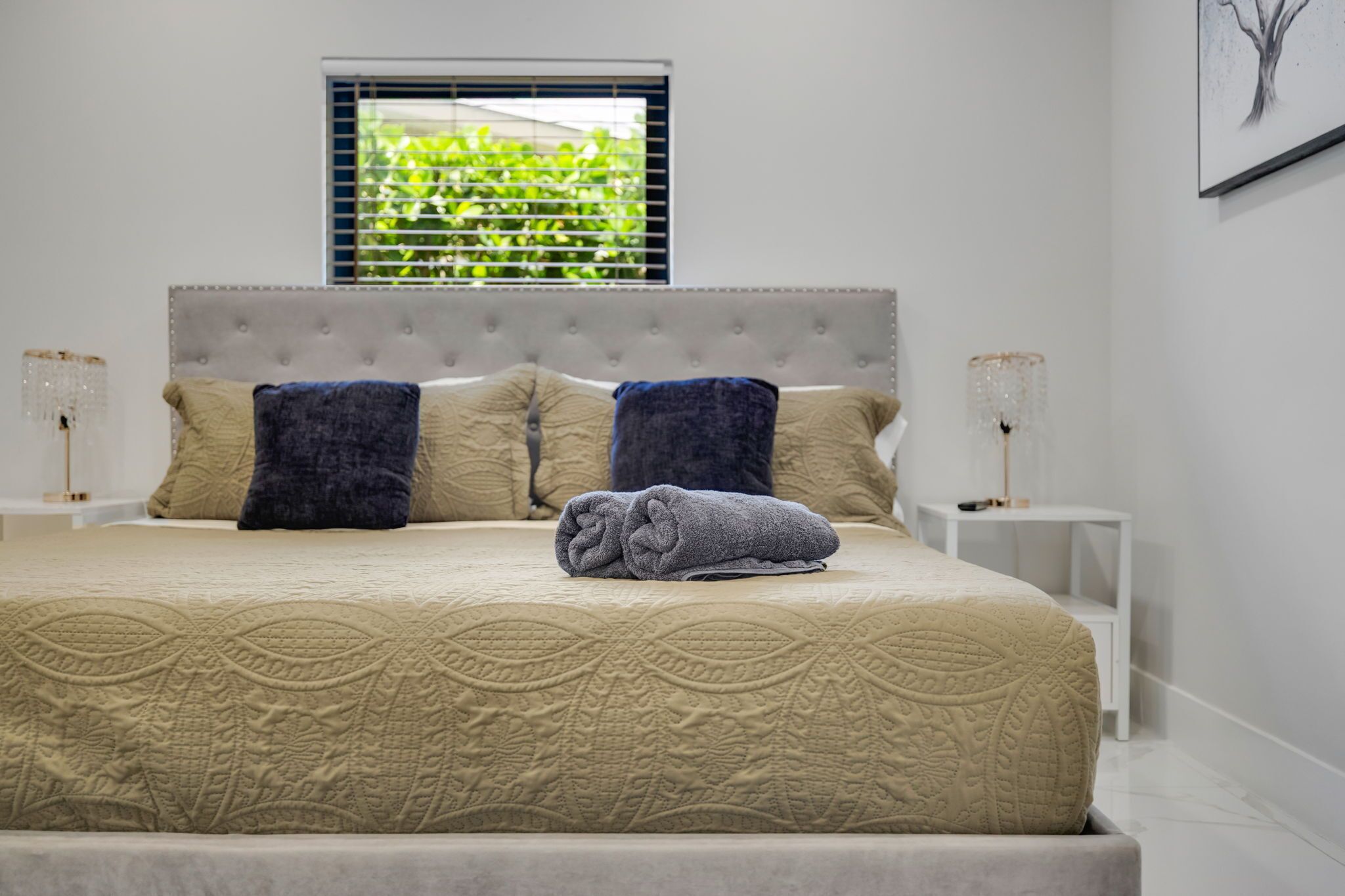 A neatly made bed with a patterned bedspread, two pillows, and a rolled towel.