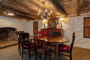 A rustic dining area with a wooden table, chairs, and a chandelier.