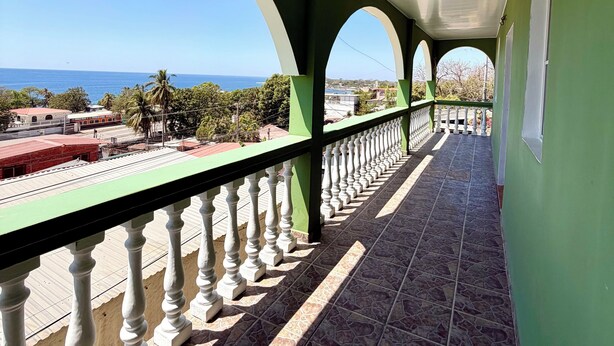 Un balcon fermé offrant une vue sur la mer et les bâtiments.