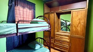 Une chambre avec des lits superposés, une armoire et une fenêtre avec des rideaux.