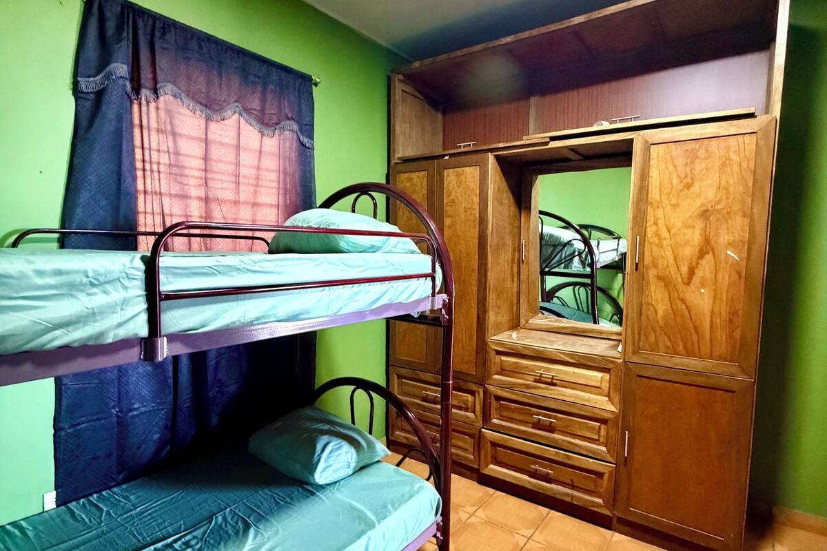 A room with bunk beds, a wardrobe, and a window with curtains.