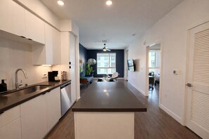 A modern kitchen with a central island, built-in appliances, and a dining area with a view. - Modern Apartment w/ Pool, Gym & 10 Min to Disney (Santa Ana)