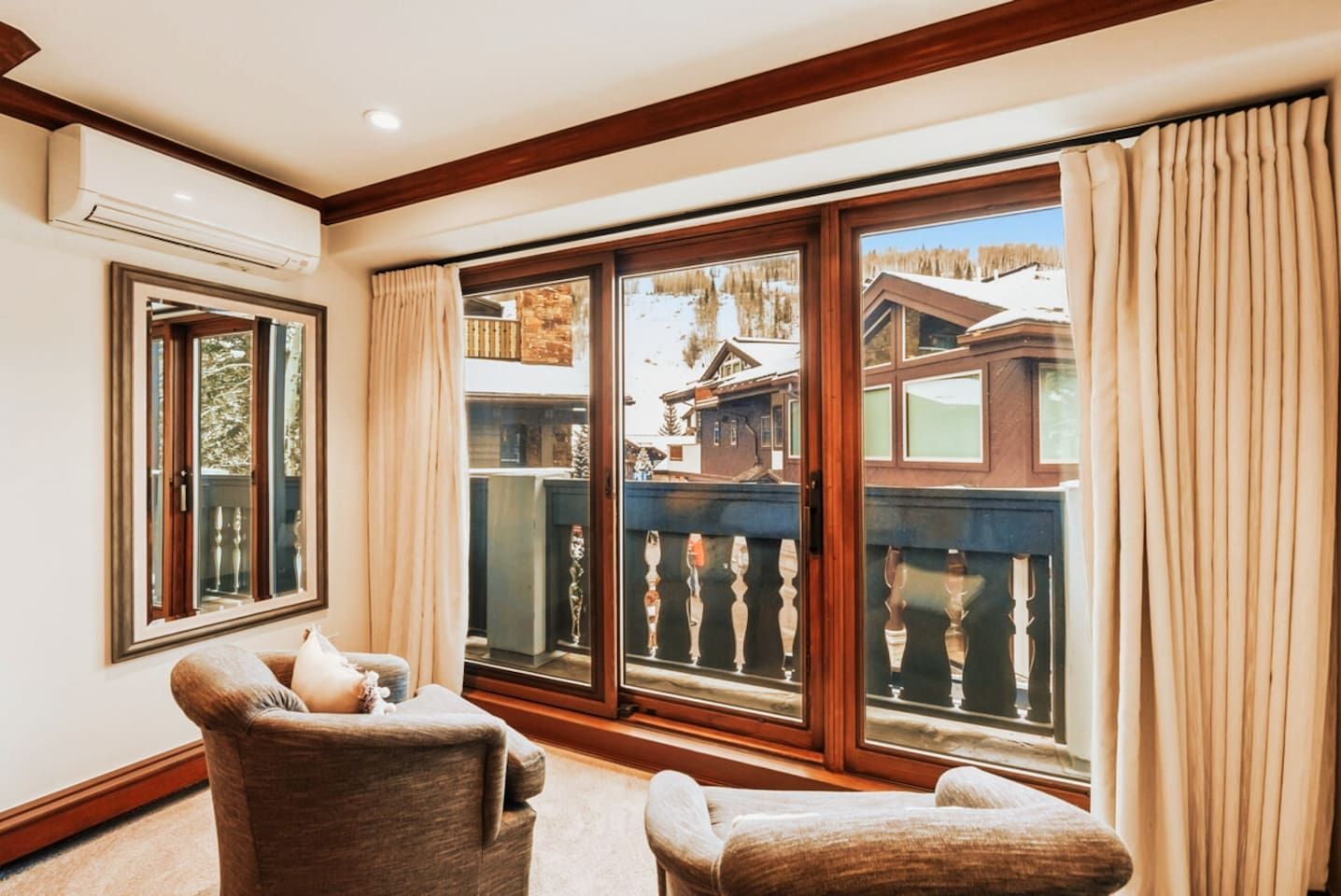 A room with a large sliding glass door leading to a balcony, a chair, and a small table.