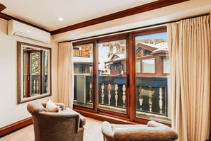A room with a large sliding glass door leading to a balcony, a chair, and a small table. - Vail Village 5BR, Sleeps Ten (Vail)