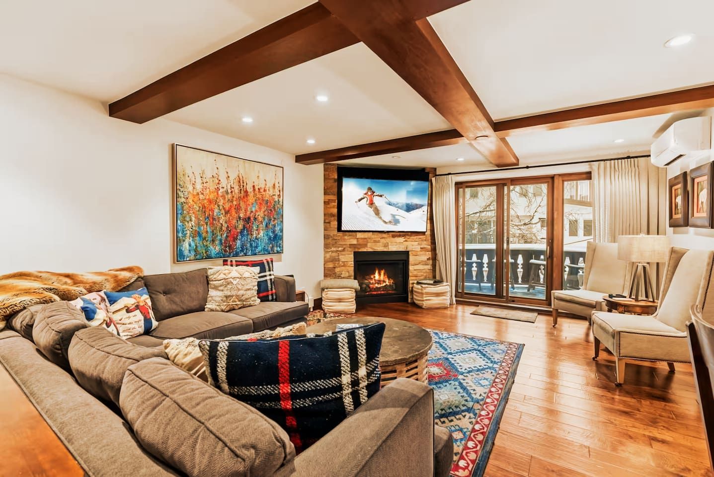 A cozy living room with a fireplace, a large TV, and a view of the outdoors.