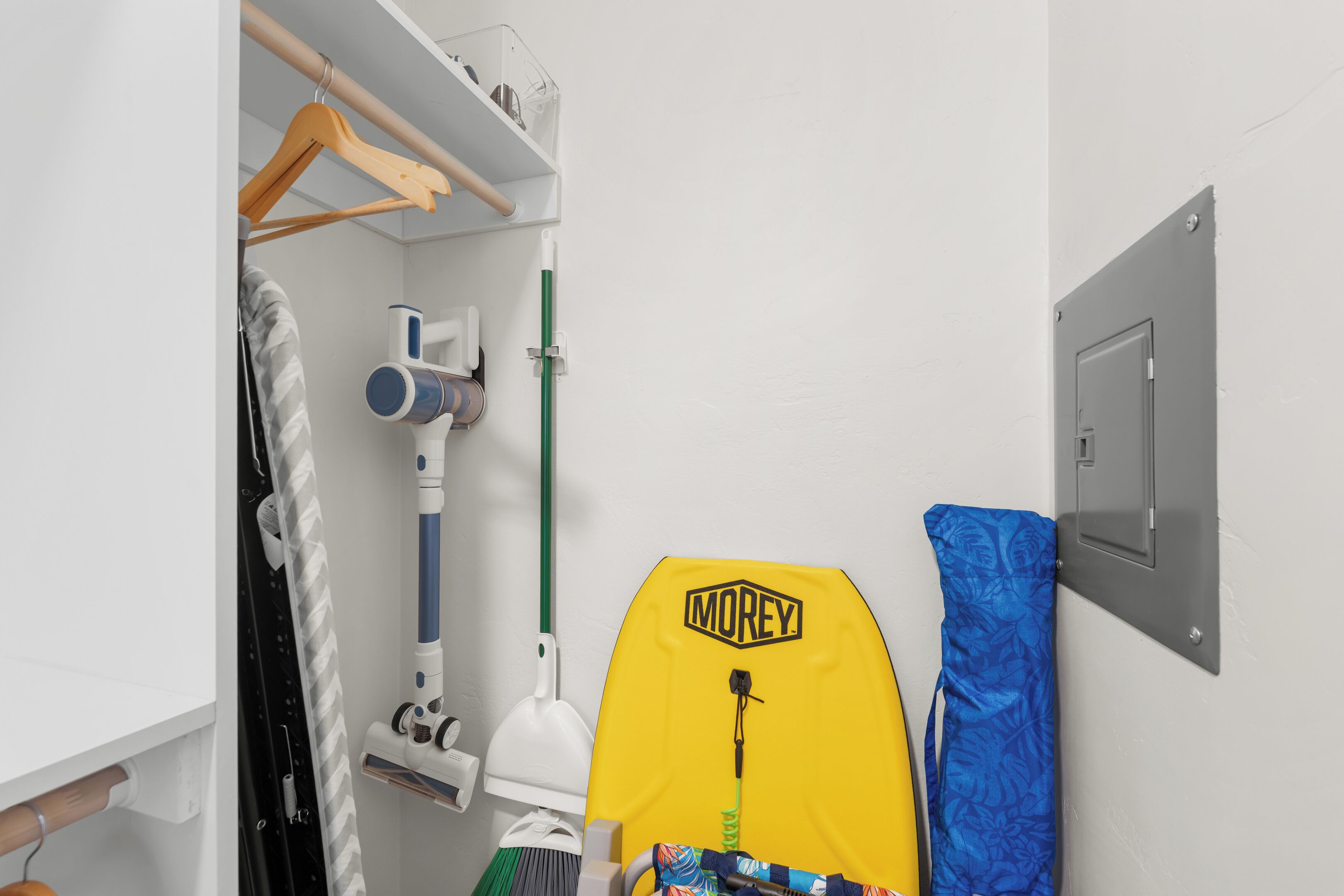 Une salle de bain avec une douche, un porte-serviettes, un sac suspendu et une planche de surf.