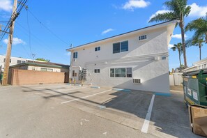 A two-story building with a parking lot in front. - Pacific Tides -Entire 9-Unit Apartment Complex w/ Parking + A/C in Pacific Beach (San Diego)