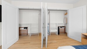 Ein Zimmer mit Holzboden, weißen Wänden und einem offenen Kleiderschrank.