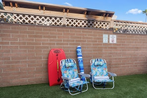 A wall with a brick pattern, two beach chairs, a red surfboard, and two signs indicating quiet hours and no poop/pee zone. - Pacific Tides -Entire 9-Unit Apartment Complex w/ Parking + A/C in Pacific Beach (San Diego)