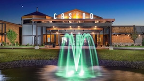 A modern building with a prominent 'CASINO' sign, a landscaped entrance, and a water feature.