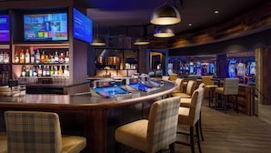 A bar area with a counter, bar stools, and arcade games.