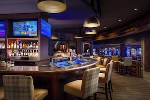 Zona de bar con mostrador, taburetes y juegos de arcade.