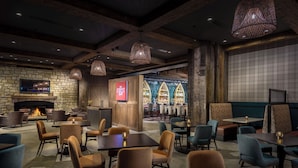 A restaurant with a stone wall, wooden ceiling, and hanging lights.