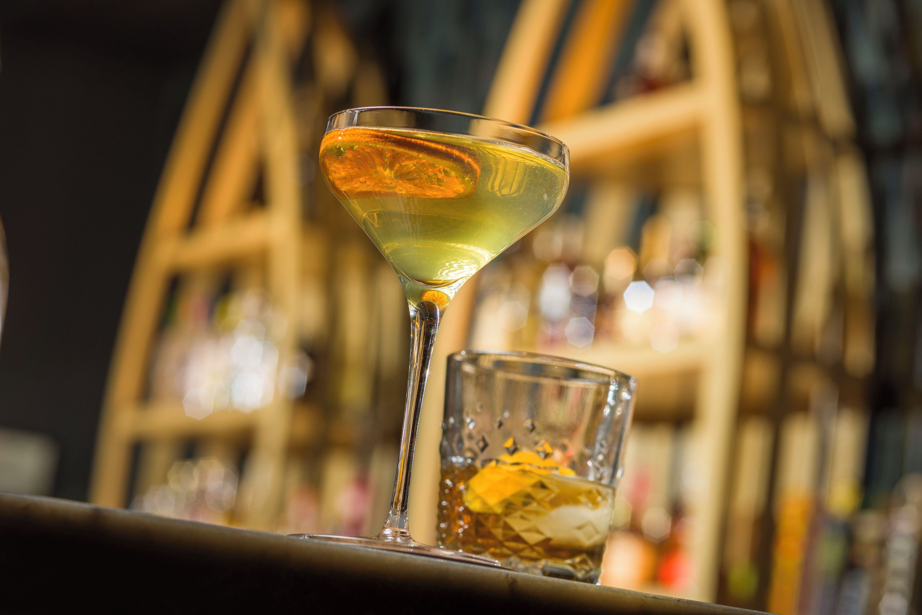 A martini glass with a yellow liquid on a bar counter.