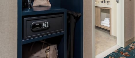 A hotel room with a wardrobe containing folded towels, a hanging bag, and a suitcase.
