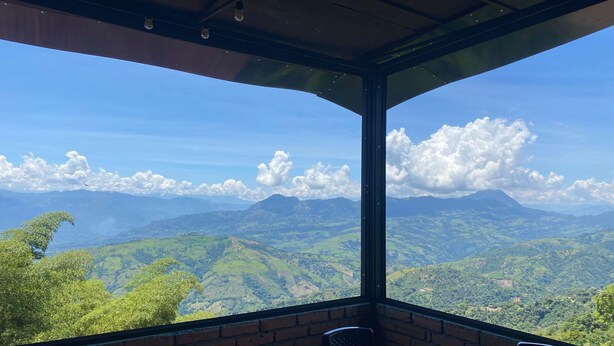 A room with a large window overlooking a mountainous landscape. - Hotel Galería Plaza (Santa Bárbara)