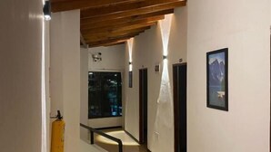 A hallway with wooden ceiling beams, a fire extinguisher, and a framed picture on the wall. - Hotel Galería Plaza (Santa Bárbara)