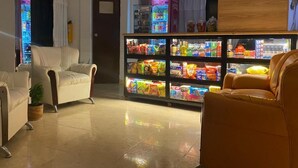 A hotel lobby with leather chairs, a vending machine, and a reception desk. - Hotel Galería Plaza (Santa Bárbara)