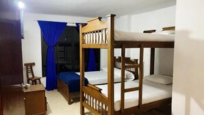 A room with bunk beds, a chair, a small table, and blue curtains. - Hotel Galería Plaza (Santa Bárbara)