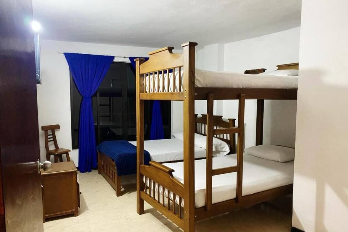 Une chambre avec des lits superposés, une chaise, une petite table et des rideaux bleus.