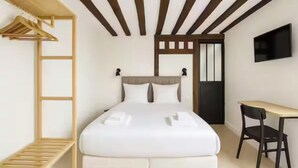 Ein Schlafzimmer mit Bett, Schreibtisch, Stuhl, Fernseher und Kleiderschrank.