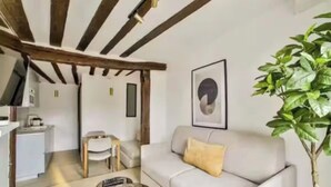 Ein Wohnzimmer mit einer Couch, einem Couchtisch und einem Essbereich mit einem Stuhl und Tisch.