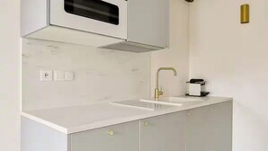 Eine moderne Küche mit weißer Arbeitsplatte, einem goldenen Wasserhahn und grauen Schränken.
