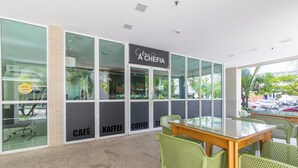 Un café avec un mur en verre, des chaises vertes et une table en bois.
