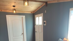 A room with a wooden floor, a bed with blue bedding, a wooden chair, and two doors. - Cozy cottage in Sto Domingo, quiet environment, close to beach and commerce. (San Antonio)