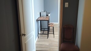 A narrow hallway with a wooden floor leading to a room with a bed and a chair. - Cozy cottage in Sto Domingo, quiet environment, close to beach and commerce. (San Antonio)