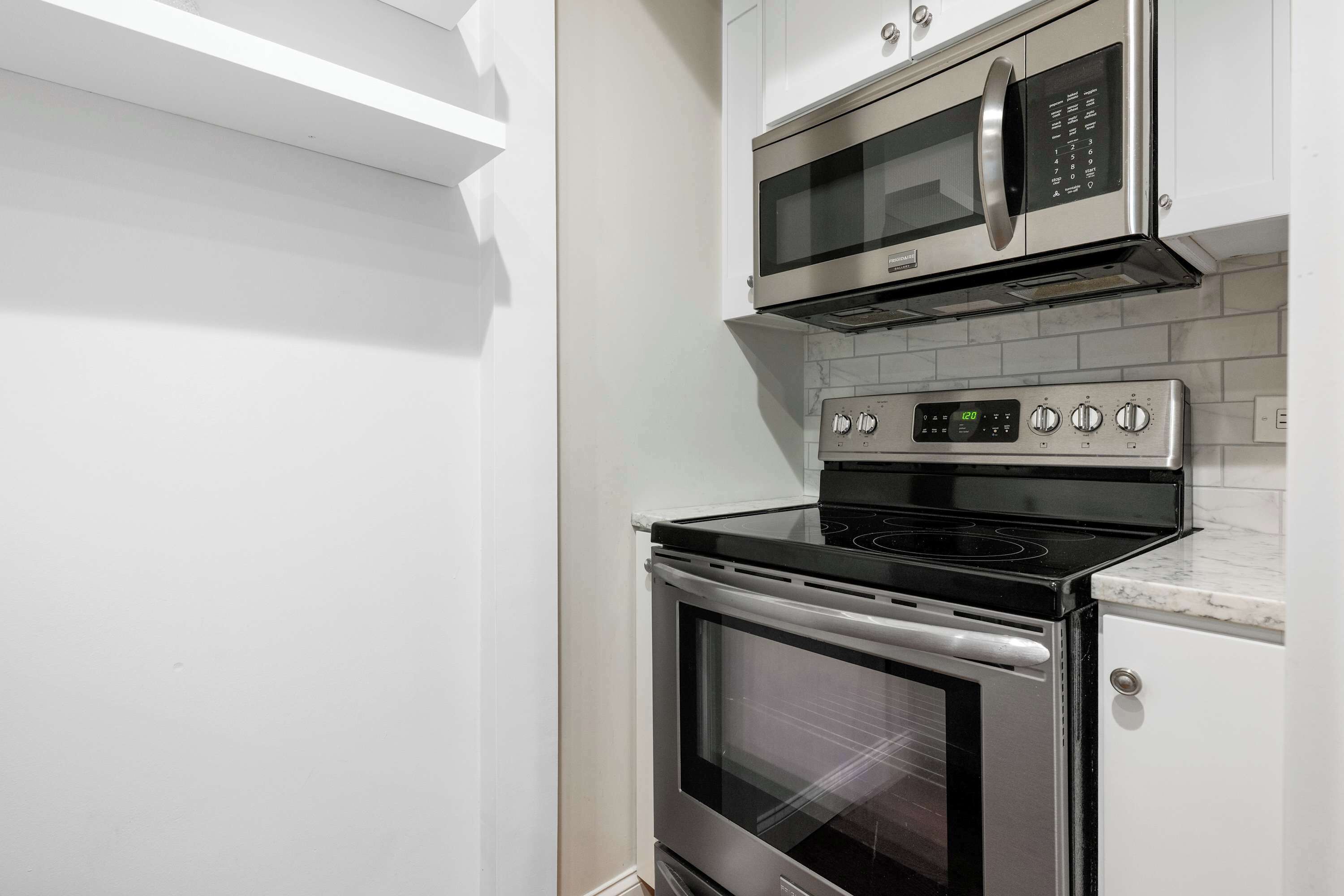 Una cocina con horno de acero inoxidable, microondas y panel de control digital.