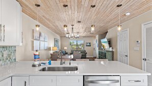 A kitchen with a central island, stainless steel appliances, and pendant lighting. - Sandprints A8 (Destin)