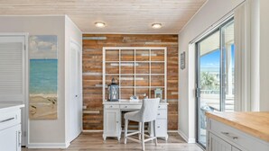 A kitchen with a wooden wall, white cabinets, and a view of the ocean. - Sandprints A8 (Destin)